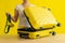 Faceless woman folds bikini in a suitcase on a yellow background. The girl is packing luggage for a trip to the trip to