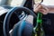 A faceless woman opens a bottle of beer while driving a car. Breaking the law and drinking alcohol while driving