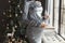 Faceless womans pregnant belly in velvet grey evening dress closeup in cozy home interior on Christmas tree background