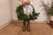 Faceless young woman holds in hands asymmetrical green Christmas wreath made from natural materials