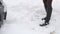 Faceless Young woman shovels a snowdrift in front of her car in snowfall