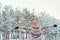 Faceless young woman standing in winter forest and enjoying falling snow. Back view