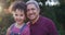 Faces of a grandfather and granddaughter smiling, bonding and hugging together in nature outside. Portrait of a little