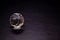 Faceted sphere, sparkling crystal on dark, black background. Large glass with light refraction, stone backdrop. Empty space for