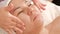 Facial massage in an Asian beauty salon. Hands of a cosmetologist apply cream on the face skin of an oriental middle