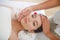 Facial massage in spa salon. Relaxation Beautiful woman lying on the bed and doing facial treatment in spa salon by masseur.