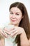 Facial portrait of young woman with tea mug in hands, grey background