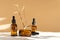 Facial serum, in three amber glass bottles with dropper lid on beige background with floral shadow. Essential oil for