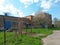 Factory brick building deserted and without people during spring blossom of trees, on background blue sky with clouds