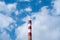 A factory chimney with rising smoke under a blue sky