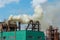 Factory chimneys against the gray autumn sky. Utopian landscape background. White toxic smoke is coming from a huge pipe.