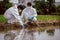 Factory scientists or biologists wear protective clothing while Collecting water samples in natural water sources near farmland.