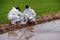 Factory scientists or biologists wear protective clothing while Collecting water samples in natural water sources near farmland.