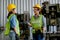 Factory woman technician or worker give wrench to her co-worker in front of machine with day light