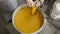 Factory worker feeling a barrel with homogenized honey with many barrels on the background