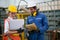 Factory worker man and woman with safety uniform discussion about robot working in factory workplace. They look happy with concept