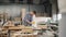 Factory worker polishing wood with electric machine in spacious workshop