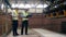 Factory workers check a machine that moves bricks.