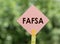 FAFSA text on pink note paper on green background