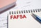 FAFSA text written on notepad with pen on financial documents