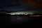 Faint aurora borealis over mountain and calm fjord