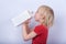 Fair-haired boy drinking milk or juice from large carton. Portrait of child with carton of milk on white background