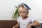 Fair-haired boy sits with book on his head. Angry little boy holding book above his head like roof