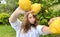 a fair-haired girl juggles lemons against the backdrop of a lemon tree in a tropical country, she is dressed in a white