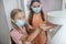 Fair-haired girl in preventive mask getting some sanitizer into her hand