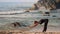 Fair haired lady does stretching exercises on ocean beach