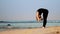 Fair haired woman practices breathing yoga on sand beach