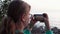 Fair-haired young woman films sunset with smartphone camera