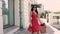 Fair-skinned young lady in red dress walking elegantly down the street