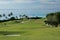 A fairway on a tropical golf course, with a view of the ocean