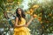 fairy tale girl walking in fabulous lemon garden. Fantasy woman in bright yellow dress pixie costume, fake plastic