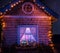 Fairy-tale house in the lights and a luminous window with a Christmas tree . Night photo.