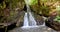 Fairy waterfall at wild forest. Wonderful fresh water waterfalls river flowing. Forest rocks with a roaring stream running. Panora