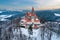 Fairytale Castle in winter. Aerial view of Romantic castle in picturesque highland landscape, covered in snow.