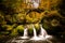 Fairytale rocky landscape with waterfall and bridge in the Ardennes forest during autumn in Luxembourg.