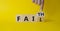 Faith vs Fail symbol. Businessman hand points at turned wooden cube with words Fail and Faith. Beautiful yellow background.