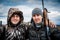 Faithful cheerful friends standing together in front of dramatic sky in overcast day during hunting season embracing each over