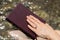 Faithful Christian woman holding closed Holy Bible in hand with a ring in nature and river.