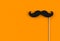 Fake black mustache on orange background