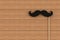 Fake black mustache on wooden board