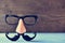 Fake mustache, nose and eyeglasses on a blue surface