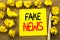 Fake News. Business concept for Hoax Journalism written on sticky note paper on the vintage background. Folded yellow papers on th