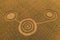 Fake UFO circles on grain crop yellow field, aerial view from drone