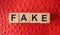 FAKE word written in wooden blocks on red leather. Fake or real news, myth or true concept