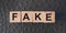 FAKE word written in wooden blocks on red leather. Fake or real news, myth or true concept