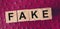 FAKE word written in wooden blocks on red leather. Fake or real news  myth or true concept